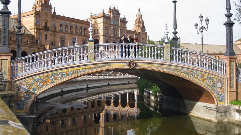学生 stand on an intricate bridge over a river in 西班牙塞维利亚