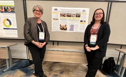 Photo of Emily Thomas and Kathryn Loukas posing in front of a research poster