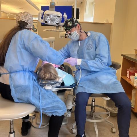 两名牙科学生在口腔健康诊所为一位病人清洁牙齿